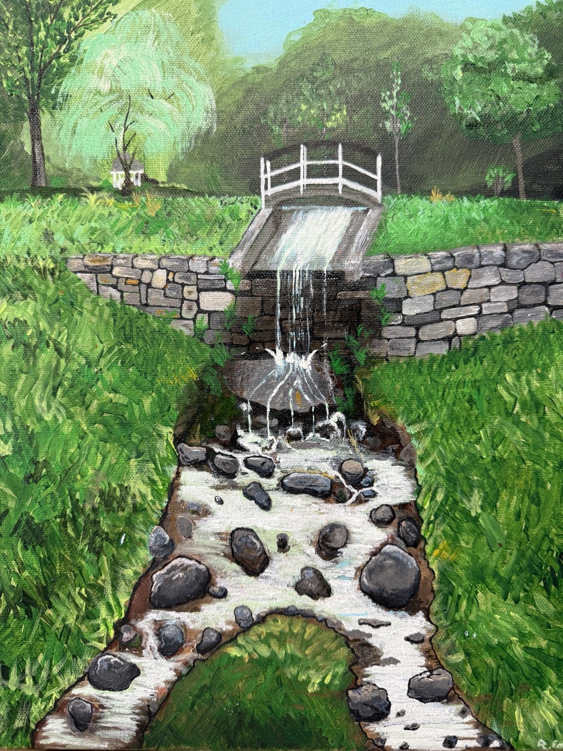 Stream cascading over stones from a small white bridge